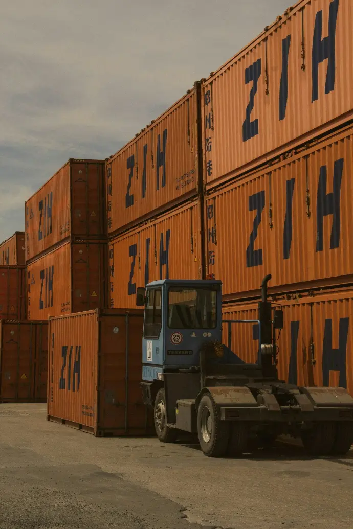 A forklift parked in front of a large stack of shipping containers